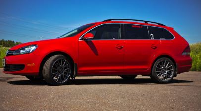 a fancy red car parking near a grassland