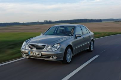 An elegant silver car cruising along a scenic grassland