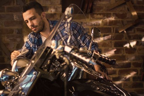 A mechanic is caring for and cleaning chrome on a motorcycle