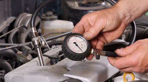 Someone doing compression test for an engine’s cylinder with a compression tester.